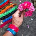Eine Hand hält eine Rosa Blume. Am Handgelenk sind Rüschenarmbänder.