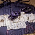 Drei Goller aus weißer Spitze liegen auf einem violetten Hintergrund.