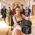 Eine Frau in rosa Tracht hält eine schwarze Tasche. Eine Frau in rosa Tracht hält eine schwarze Tasche.