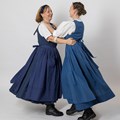 Zwei Frauen im blauen Werktagsgwand tanzen miteinander.