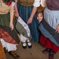 Ein kleines Mädchen schaut zwischen Tanzröcken hervor.