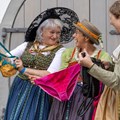 Drei Frauen in Tracht betrachten Unterwäsche und lachen dabei