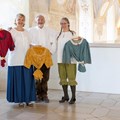 Drei Menschen mit Trachtenblusen in den Händen