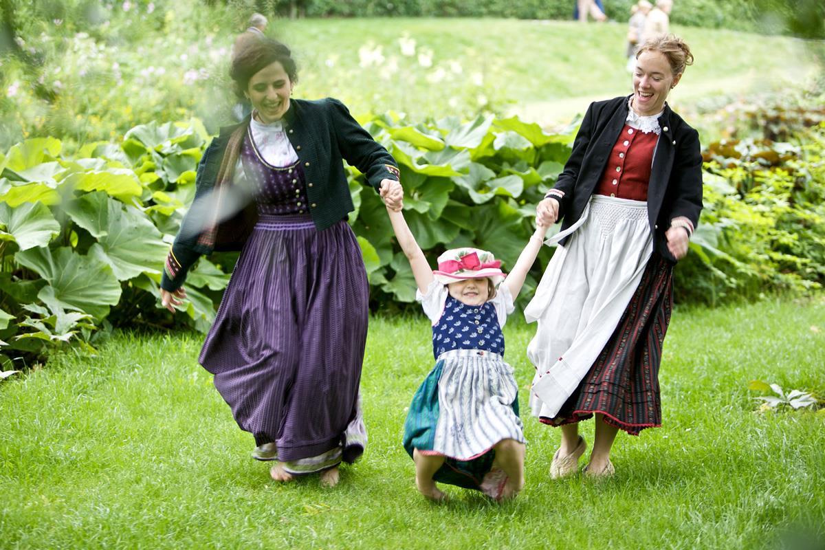 Zwei Frauen in Kitteljacke mit einem Kind in der Mitte