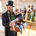 Ein Mann mit Bauchladen und eine Gruppe von Menschen in Tracht. Ein Mann mit Bauchladen und eine Gruppe von Menschen in Tracht.